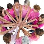 Cheerful women joined in a circle wearing pink for breast cancer on white background